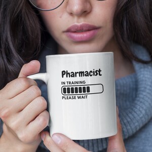 May include: White ceramic mug with black text that reads "Pharmacist in Training" and a progress bar that says "Please Wait".