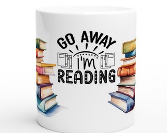 May include: White ceramic mug with black text that reads "Go Away I'm Reading" with a stack of colorful books on either side of the text.