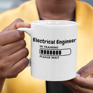 Può includere: Una tazza in ceramica bianca con testo nero che recita "Electrical Engineer In Training" con una barra di avanzamento e le parole "Please Wait".