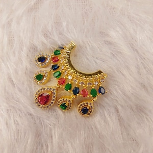 May include: Gold earring with a crescent shape and multiple teardrop-shaped stones. The stones are clear, red, green, and blue.