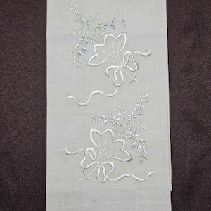 May include: A white linen hand towel with embroidered white floral designs. The towel has a delicate, vintage look.