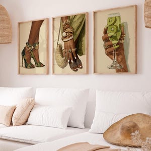 Puede incluir: Tres impresiones artísticas enmarcadas con ilustraciones de accesorios de moda. Una impresión muestra zapatos de tacón alto, otra un bolso y joyas, y la tercera una mano sosteniendo un cóctel con rodajas de kiwi. Las impresiones tienen una paleta de colores neutros.