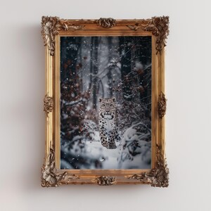 May include: A snow leopard stands in a snowy woodland, looking directly at the camera. The leopard is brown and white with black spots. The woodland is covered in snow and there are trees in the background.