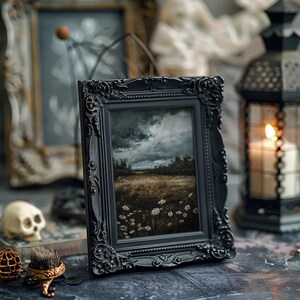 May include: A black framed painting of a landscape with a cloudy sky and a field of white flowers. The painting is in a dark, ornate frame.