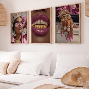 Puede incluir: Conjunto de tres impresiones artísticas enmarcadas. Una presenta a una mujer con corona y gafas de sol, otra muestra unos labios con dientes de oro, y la tercera muestra una mano adornada con joyas y uñas largas de color rosa. Tema moderno y glamuroso.