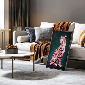 May include: A framed print of a pink cheetah sitting on a green background. The cheetah has black spots and is looking to the right. The print is in a modern style and would look great in a living room or bedroom.