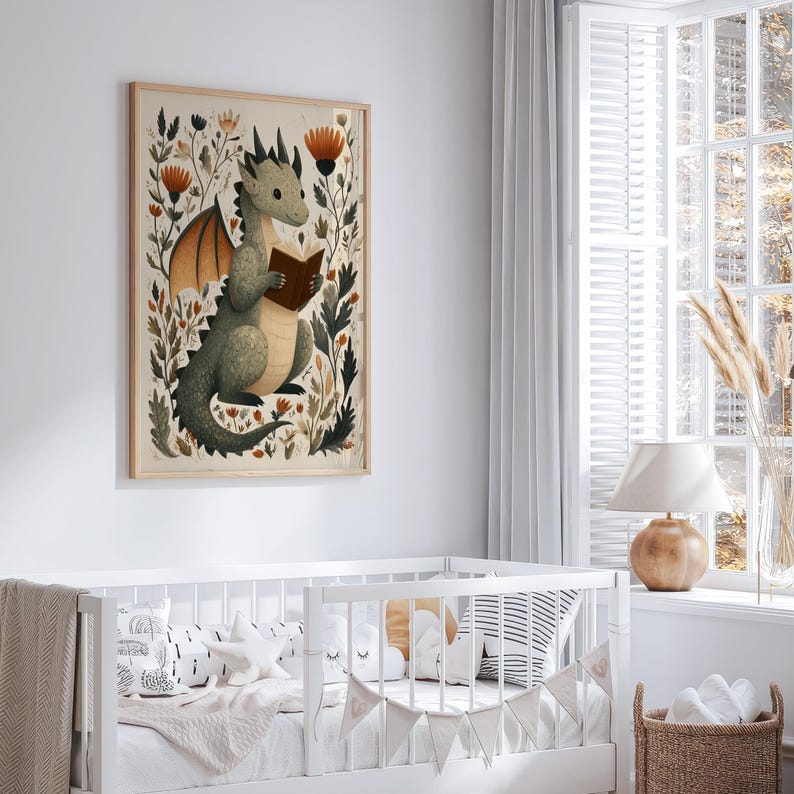 May include: A framed art print featuring a whimsical illustration of a green dragon reading a book. The dragon is surrounded by floral elements in shades of brown, orange, and green. The artwork is displayed above a white crib, creating a cozy nursery theme.
