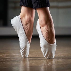 May include: A pair of white leather ballet slippers with a soft, flexible construction and a rounded toe design. The slippers feature a low-cut profile that contours to the foot, providing a snug fit for movement. The text AntepStoreCo is visible.