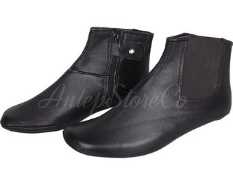 Puede incluir: Un par de botines de cuero negro con cremallera lateral. Los botines tienen la punta redonda y una suela plana.