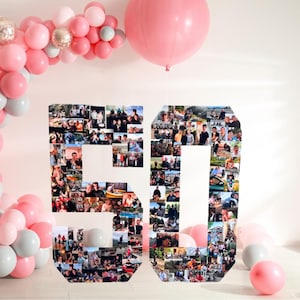 May include: A large number 50 display constructed from a collage of numerous small rectangular photographs, surrounded by a decorative arch and scattered clusters of pink, white, and silver balloons in various sizes for a celebratory event.