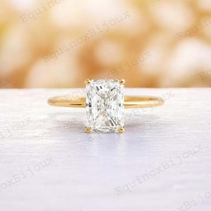 Può includere: Un anello di fidanzamento in oro con un diamante a taglio smeraldo quadrato.