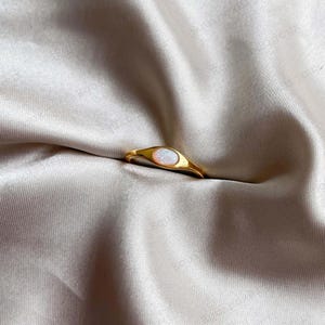May include: A gold ring with a white opal stone set in a oval shape.