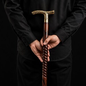 Puede incluir: Un bast&oacute;n con un eje de madera de color marr&oacute;n oscuro que presenta un dise&ntilde;o de torsi&oacute;n en espiral. El mango est&aacute; hecho de metal pulido en tono dorado y est&aacute; intrincadamente grabado con un patr&oacute;n floral detallado, unido por una banda lisa.