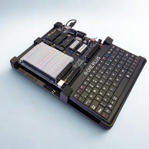 Puede incluir: Un dispositivo electrónico negro y gris con teclado y placa de circuito. El dispositivo tiene una placa de pruebas, varios chips y el texto "A-ONE PLUS". Un cable USB está conectado. El teclado es negro con letras blancas.