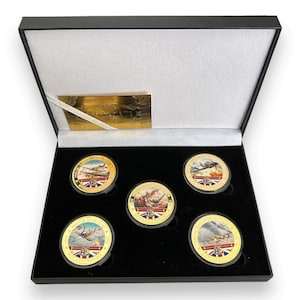 May include: A black box with a gold interior containing five gold coins with images of aeroplanes from World War II. The coins are part of a set commemorating the 80th anniversary of the Battle of Britain.
