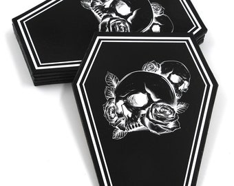 Può includere: Set di sei sottobicchieri neri a forma di bara con bordi bianchi. Ogni sottobicchiere presenta un teschio bianco con rose e foglie.