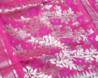 May include: Bright pink fabric with a silver floral pattern. The design features detailed silver leaves and flowers, creating a textured look. The fabric has a shiny appearance, with a striped border.