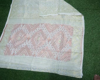 May include: A light green and white textile with a geometric pattern in shades of pink and gold. The fabric is folded, revealing the design. The textile is likely a scarf or shawl.