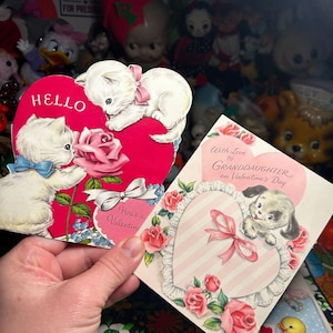 May include: Two vintage Valentine's Day cards. One card features white kittens on a red heart with the word "HELLO". The other card has a puppy on a pink heart with roses and the text "With Love to Granddaughter on Valentine's Day".