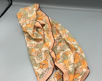 Peut inclure: Un foulard en soie à motifs pêche et vert avec une bordure marron. Le foulard porte une étiquette indiquant "Scarves by Vivienne, Made in Japan".