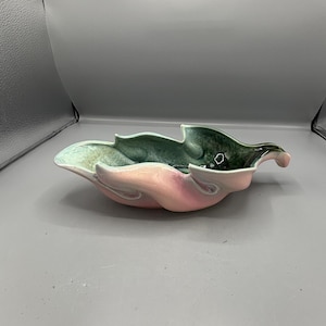 May include: A ceramic leaf-shaped bowl with a glossy finish. The bowl features a gradient of colors, including pink, green, and a touch of blue. The design is organic and decorative, suitable for serving or display.