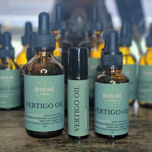 May include: Three brown glass bottles of Vertigo Oil with black droppers and a roll-on bottle. The labels are light green with the text "VERTIGO OIL" and "HERBCORE FUSIONS". The bottles are on a wooden surface.