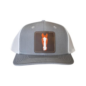 May include: A gray and white trucker hat with a brown leather patch featuring a white horse head silhouette with orange mane and muzzle.