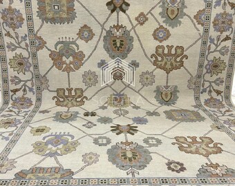 May include: A beige rug with a floral pattern in shades of brown, green, and blue. The rug has a border with a repeating geometric design.