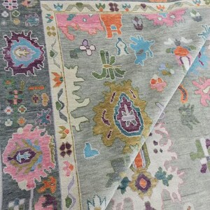 Pu&ograve; includere: Primo piano di un tappeto grigio con un motivo floreale colorato. Il tappeto ha uno sfondo grigio chiaro con una variet&agrave; di colori, tra cui rosa, blu, verde e giallo. Il motivo &egrave; intricato e dettagliato, e il tappeto &egrave; realizzato in un materiale morbido e lussuoso.