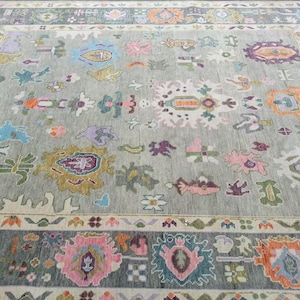 Pu&ograve; includere: Un tappeto grigio con un motivo intricato e colorato. Il tappeto presenta una variet&agrave; di forme geometriche e motivi floreali in tonalit&agrave; di rosa, blu, verde, giallo e arancione.