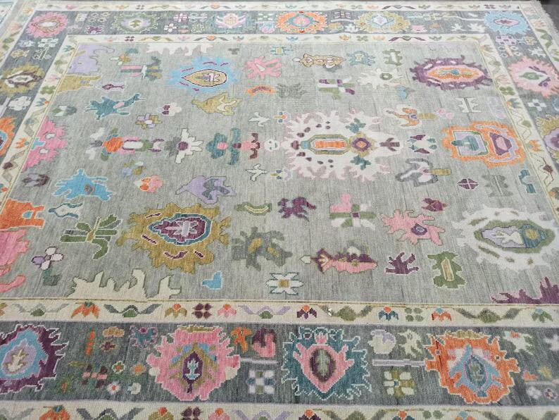 Pu&ograve; includere: Un tappeto grigio con un motivo intricato e colorato. Il tappeto presenta una variet&agrave; di forme geometriche e motivi floreali in tonalit&agrave; di rosa, blu, verde, giallo e arancione.