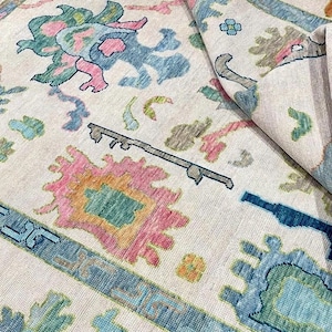 May include: A cream-colored rug with a repeating pattern of blue, green, pink, and orange floral designs. The rug has a distressed, vintage look.