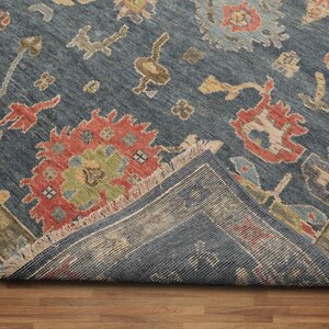 May include: A blue rug with a traditional Persian design featuring red, green, and beige accents. The rug has a fringed edge and is folded in half.