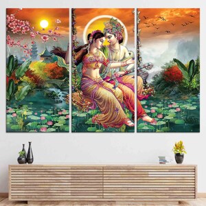 Puede incluir: Una impresi&oacute;n en lienzo de tres paneles que representa una ilustraci&oacute;n colorida de una pareja en un columpio en un entorno tropical exuberante. La pareja est&aacute; vestida con ropa tradicional india y est&aacute; rodeada de flores y follaje. El fondo presenta un cielo de puesta de sol y una cordillera distante.