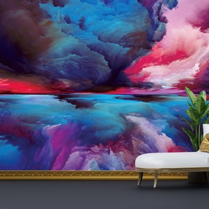 May include: Abstract painting depicting a colourful sky with clouds and a reflection in the water below. The painting is framed in gold and displayed in a room with a white chaise lounge and a green plant.