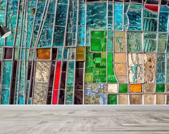 May include: A colorful stained glass wall with a variety of rectangular and square shapes in shades of teal, green, orange, red, and purple. A black floor lamp with a round base and a black lampshade stands in front of the wall.
