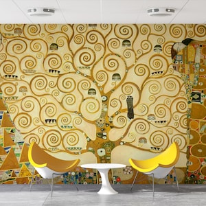 May include: A wall mural featuring a painting of a tree with swirling branches and two figures in the background. The tree is painted in shades of gold and brown, and the figures are painted in a more abstract style. The mural is set in a room with two yellow chairs and a white table.