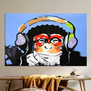 May include: A colorful painting of a monkey wearing headphones. The monkey is depicted in a pop art style with bold colors and black outlines. The background is a light blue.