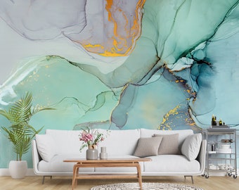 May include: Abstract wall art featuring a green, blue, and gold watercolor design. The art is displayed in a living room setting with a white sofa, a wooden coffee table, and a potted plant.