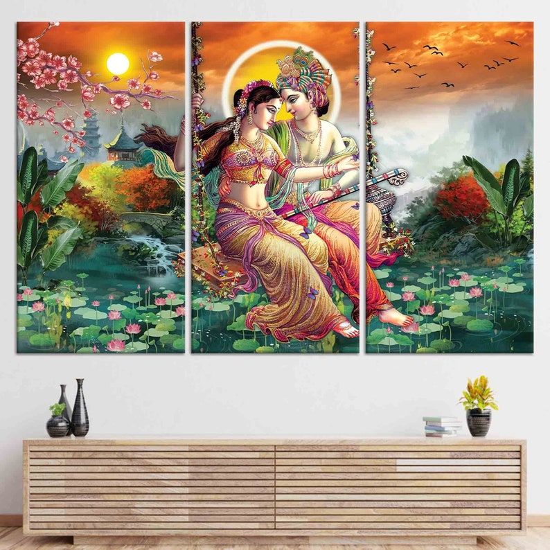 Puede incluir: Una impresi&oacute;n en lienzo de tres paneles que representa una ilustraci&oacute;n colorida de una pareja en un columpio en un entorno tropical exuberante. La pareja est&aacute; vestida con ropa tradicional india y est&aacute; rodeada de flores y follaje. El fondo presenta un cielo de puesta de sol y una cordillera distante.