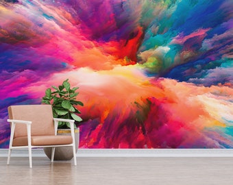 May include: Abstract art print featuring a colorful explosion of paint in shades of pink, purple, blue, green, orange, and yellow. The print is displayed on a wall with a chair and a plant in front of it.
