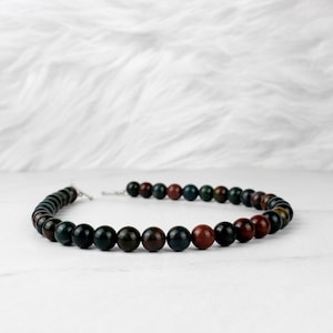 May include: A necklace made of dark green, red, and brown gemstone beads.