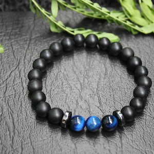 May include: Black beaded bracelet with three blue tiger's eye beads.