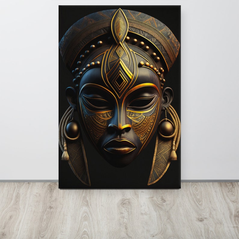 May include: A canvas print featuring a stylized African mask. The mask is primarily black with intricate gold-colored details, including geometric patterns and decorative elements. The mask has a serene expression and is displayed against a black background.