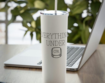 Könnte beinhalten: Weißer isolierter Becher mit silbernem Deckel und Strohhalm. Der Becher trägt den schwarzen Text "EVERYTHING UNDER CTRL". Ein Laptop, Stift und Notizblock befinden sich im Hintergrund.