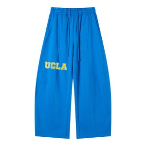 Può includere: Pantaloni blu brillante a gamba larga con vita con coulisse e tasche laterali. Il testo "UCLA" è stampato in giallo sulla gamba sinistra. I pantaloni hanno cuciture verticali sulla parte anteriore e posteriore di ogni gamba.