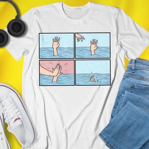 May include: White t-shirt with a graphic of a comic-style illustration of a hand reaching out of the water, followed by a hand slapping the water, and then a hand sinking below the water.