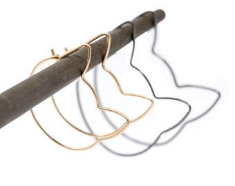 Pode incluir: Um par de brincos de argola de ouro em forma de gato e um par de brincos de argola de prata em forma de gato.