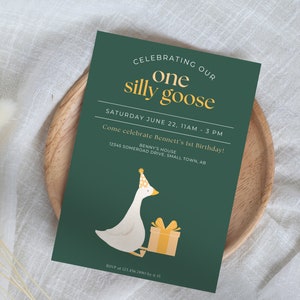 May include: A green invitation card with gold text that reads "Celebrating our one silly goose". The card has a cartoon illustration of a goose wearing a party hat and holding a gift box.