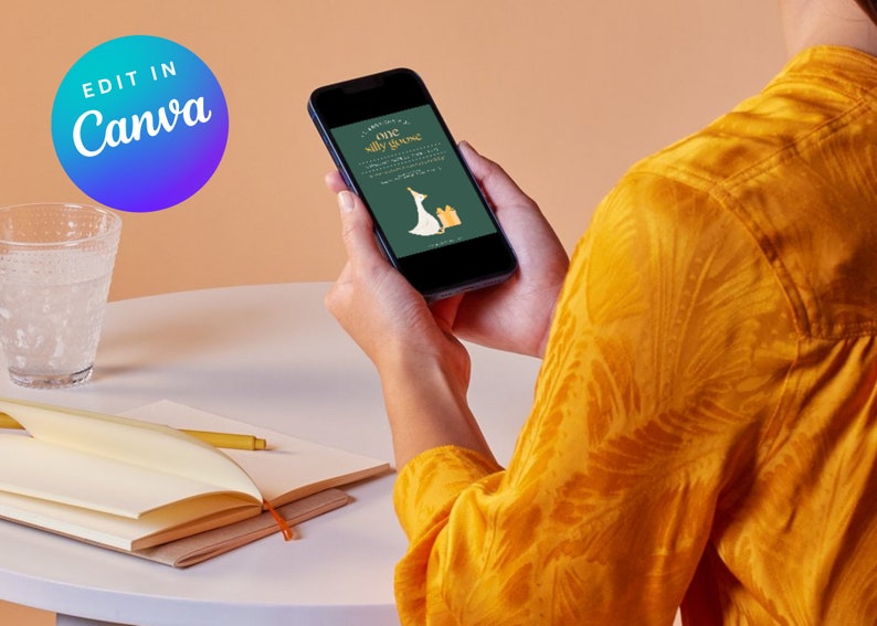May include: A person is holding a smartphone displaying a green and gold invitation with a cartoon goose wearing a party hat. The invitation reads "One Silly Goose".